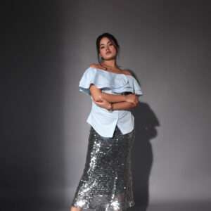 Woman wearing a silver sequin bodycon midi skirt styled for a party or evening event, paired with black heels on a neutral background